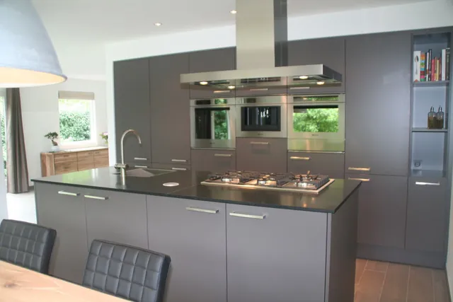 Grijze maatwerk keuken met kookeiland en hoge inbouwkasten