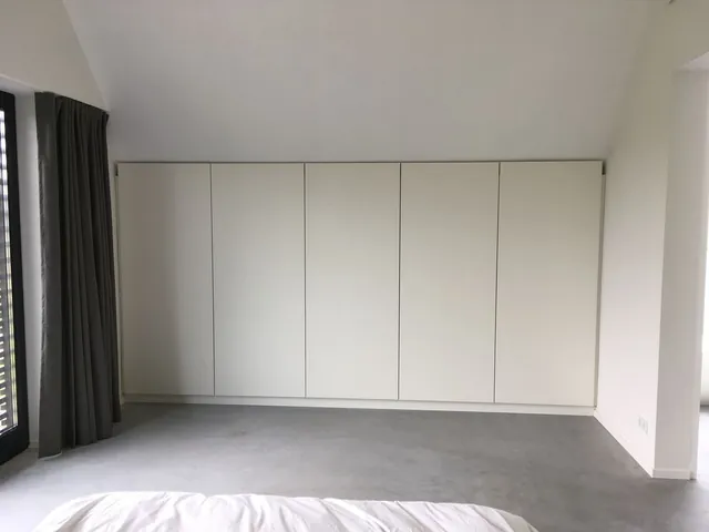 Witte greeploze kastenwand onder een schuin dak